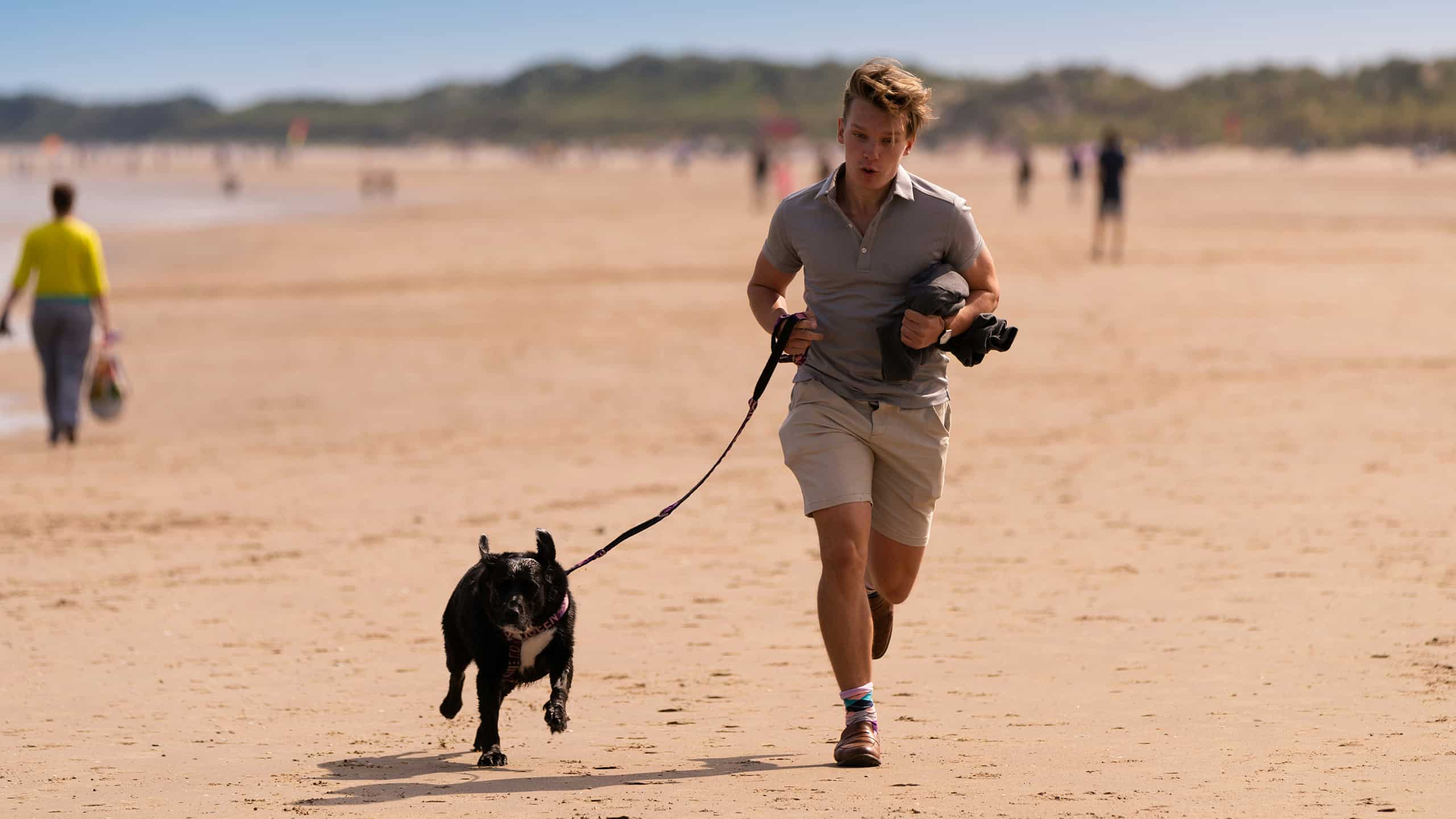 man running on beach with dog